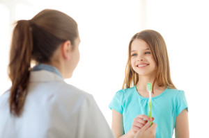 Dottoressa porge un dentifricio in mano ad una bambina